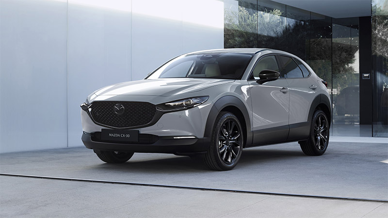 Mazda CX-30 in Grau vor moderner Architektur mit Glasfront
