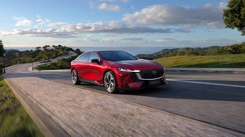 Mazda 6e fährt auf kurvenreicher Küstenstraße mit Blick auf das Meer